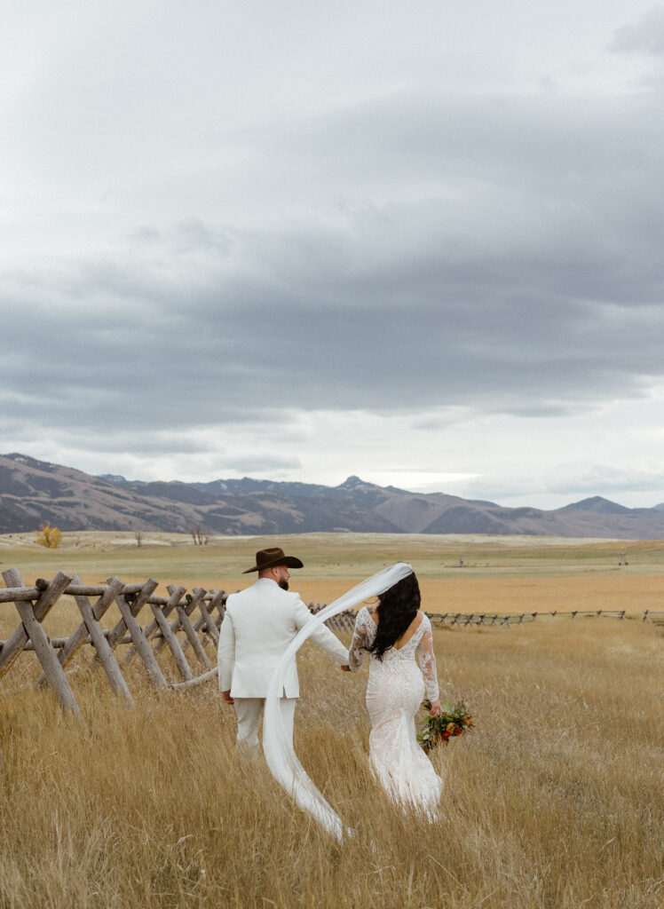 Bride and groom walk through a field in Paradise Valley Montana during their wedding day at Sage Lodge