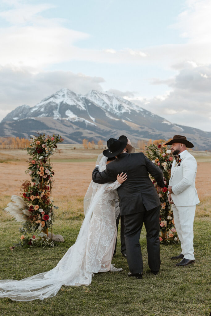 father of the bride hands her to groom during Sage Lodge wedding ceremony in Paradise Valley Montana